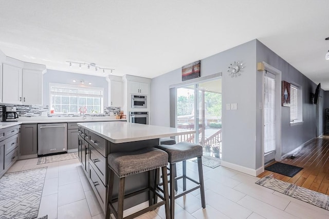 kitchen featuring gray cabinets, backsplash, a healthy amount of sunlight, and stainless steel appliances