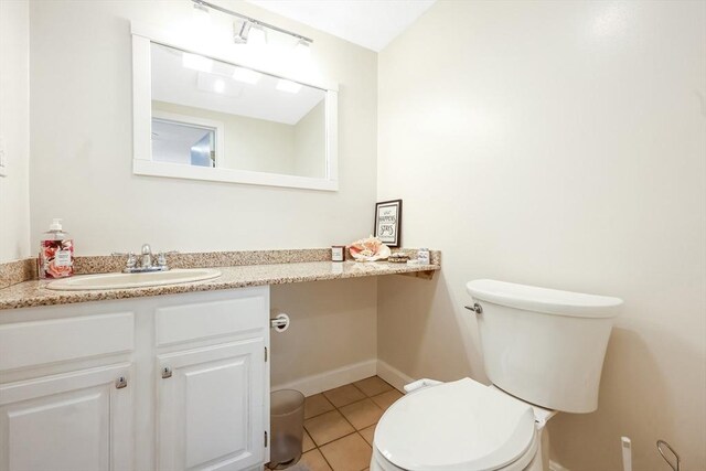 bathroom with toilet, vanity, tile patterned floors, and baseboards