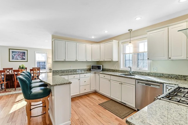 kitchen with white cabinetry, appliances with stainless steel finishes, sink, and pendant lighting