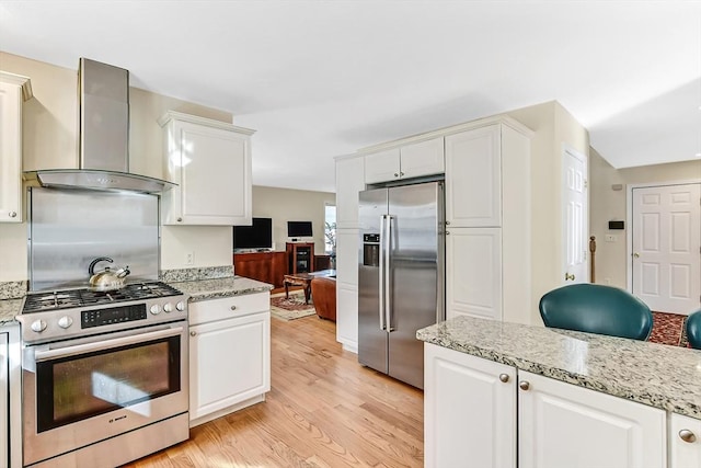 kitchen with wall chimney exhaust hood, appliances with stainless steel finishes, light hardwood / wood-style flooring, and white cabinets