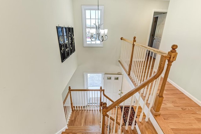 staircase featuring an inviting chandelier and hardwood / wood-style floors