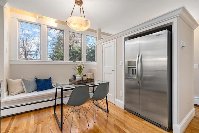 interior space with baseboards, breakfast area, a baseboard radiator, and light wood-style floors