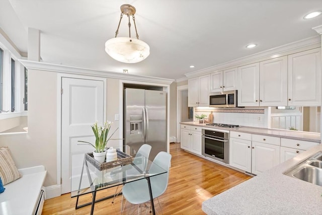 kitchen with light wood-style flooring, stainless steel appliances, white cabinetry, light countertops, and tasteful backsplash