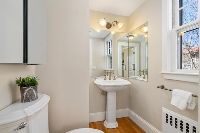 bathroom with radiator, toilet, baseboards, and wood finished floors