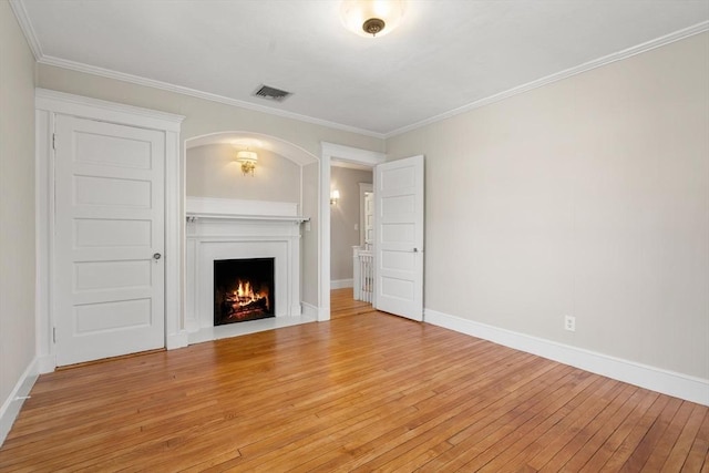 unfurnished living room featuring visible vents, a fireplace with flush hearth, ornamental molding, light wood-type flooring, and baseboards