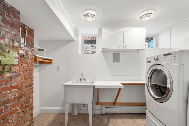 laundry area featuring brick wall, cabinet space, carpet flooring, and washer / dryer