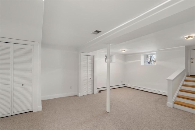 below grade area with carpet floors, a baseboard radiator, visible vents, stairway, and baseboards