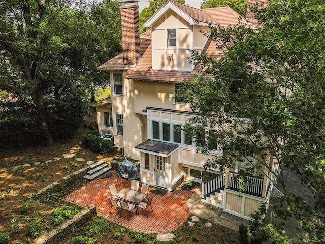 back of house with a chimney and stucco siding