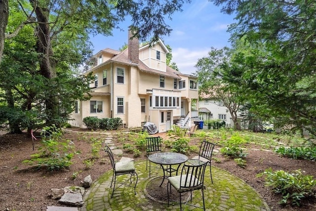 back of property featuring a balcony, a chimney, and stucco siding