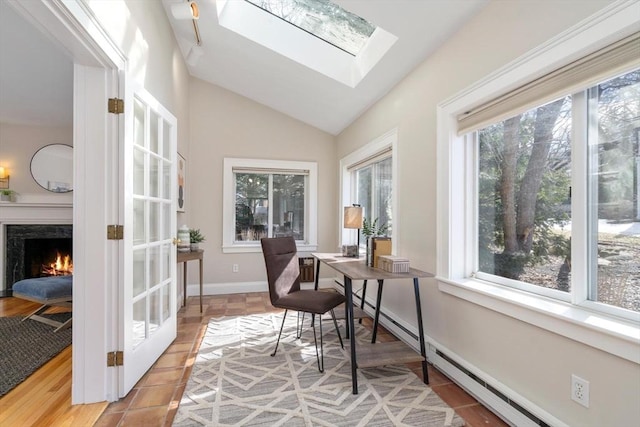 home office featuring vaulted ceiling with skylight, a fireplace, and baseboards