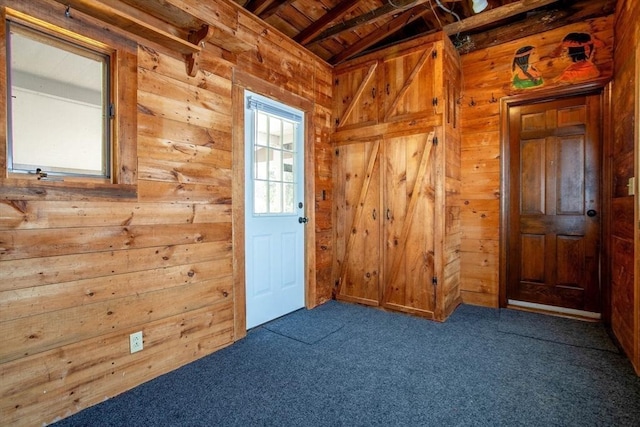 doorway to outside with dark carpet, vaulted ceiling with beams, wood ceiling, and wood walls