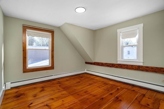 additional living space with a baseboard heating unit, hardwood / wood-style flooring, and vaulted ceiling