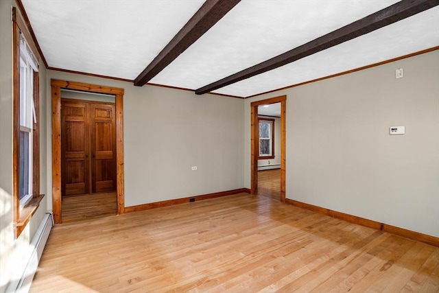 unfurnished room with a baseboard heating unit, a wealth of natural light, and light hardwood / wood-style floors