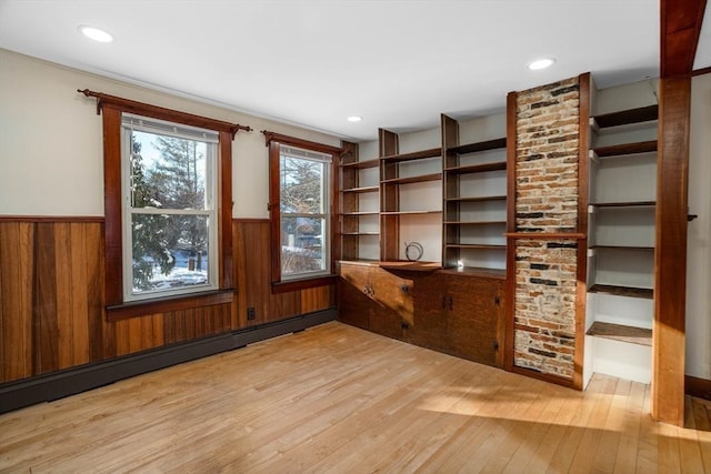 interior space with wood walls, a baseboard heating unit, and light wood-type flooring