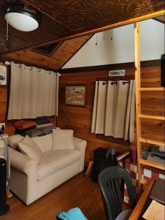 living area with wood walls, wood finished floors, and vaulted ceiling