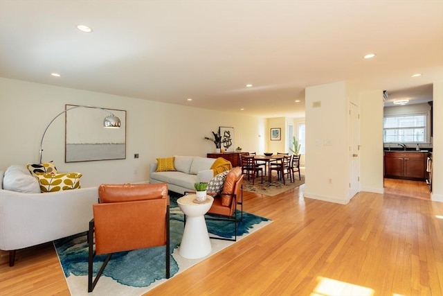 living area with baseboards, light wood finished floors, and recessed lighting