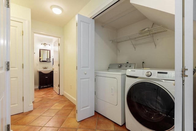 laundry area with laundry area, light tile patterned floors, baseboards, separate washer and dryer, and a sink