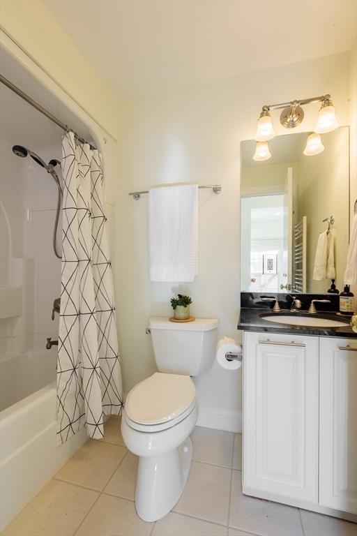 full bathroom with toilet, tile patterned flooring, shower / bath combination with curtain, and vanity