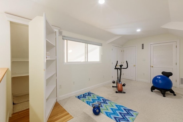 exercise room featuring visible vents, vaulted ceiling, and baseboards