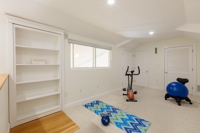 exercise area with lofted ceiling, visible vents, and baseboards