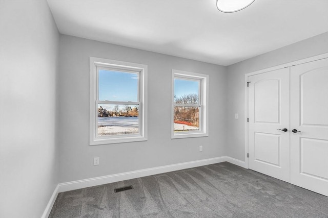 unfurnished bedroom with a closet, carpet flooring, visible vents, and baseboards