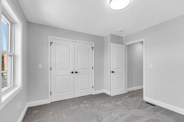 unfurnished bedroom featuring carpet floors, multiple windows, and baseboards