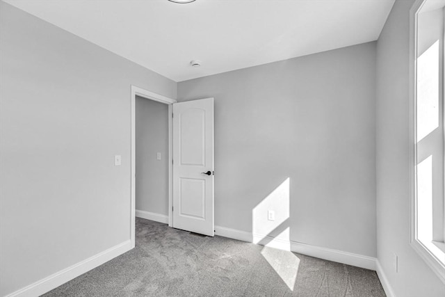 carpeted spare room featuring baseboards