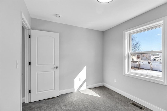 unfurnished room with carpet, visible vents, and baseboards