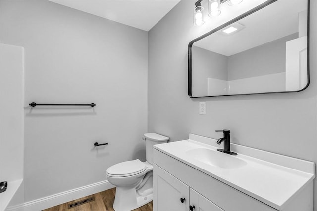 bathroom with toilet, wood finished floors, vanity, visible vents, and baseboards