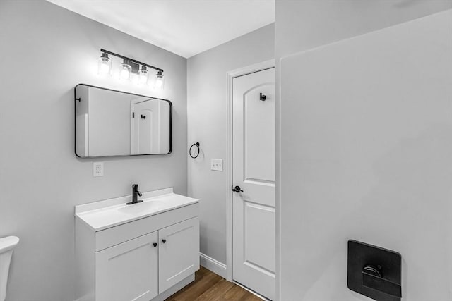 bathroom with toilet, wood finished floors, and vanity