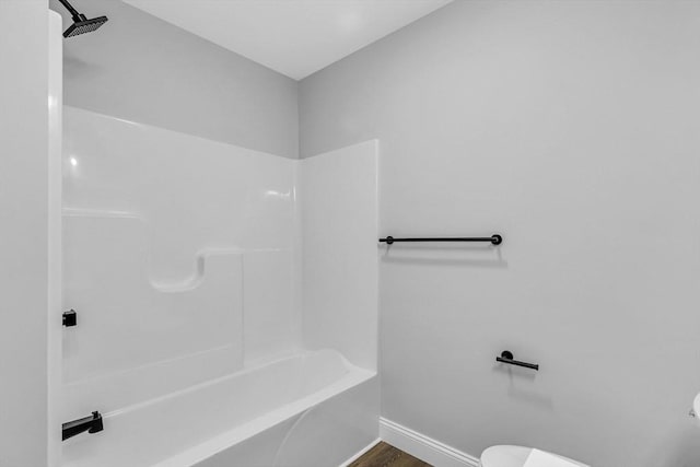 full bath with  shower combination, wood finished floors, toilet, and baseboards