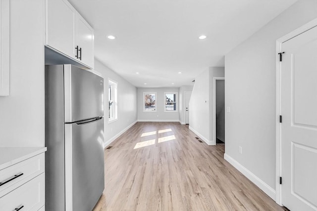 kitchen with recessed lighting, freestanding refrigerator, white cabinets, light wood-type flooring, and baseboards