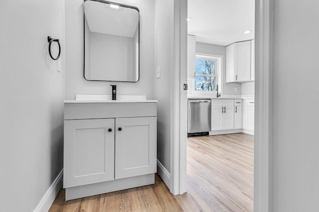 bathroom with baseboards, wood finished floors, and vanity