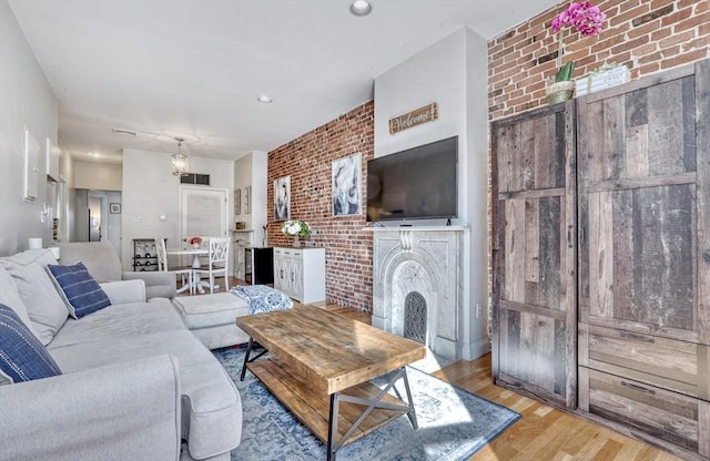 living room featuring brick wall, a fireplace, and light wood-type flooring