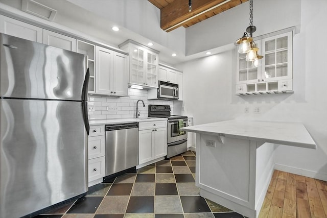 kitchen with white cabinetry, beamed ceiling, decorative light fixtures, a breakfast bar area, and appliances with stainless steel finishes