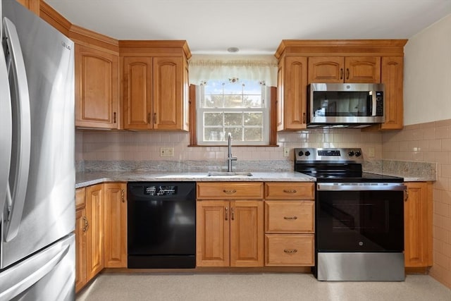 kitchen with backsplash, appliances with stainless steel finishes, light stone counters, and a sink