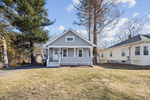 bungalow featuring aphalt driveway, covered porch, and a front yard