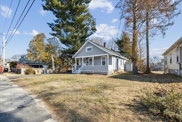 view of front of house with a chimney, a porch, and a front yard