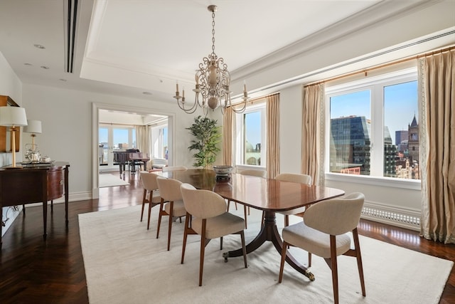 dining area with a tray ceiling, a healthy amount of sunlight, dark parquet floors, and a chandelier