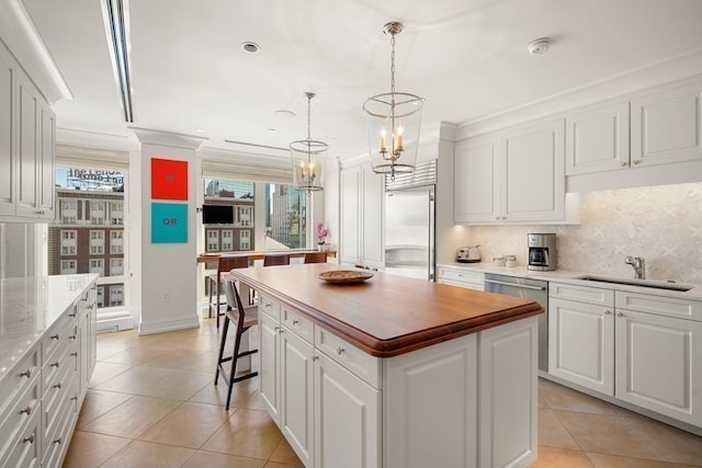 kitchen featuring tasteful backsplash, white cabinets, appliances with stainless steel finishes, a center island, and light tile patterned flooring