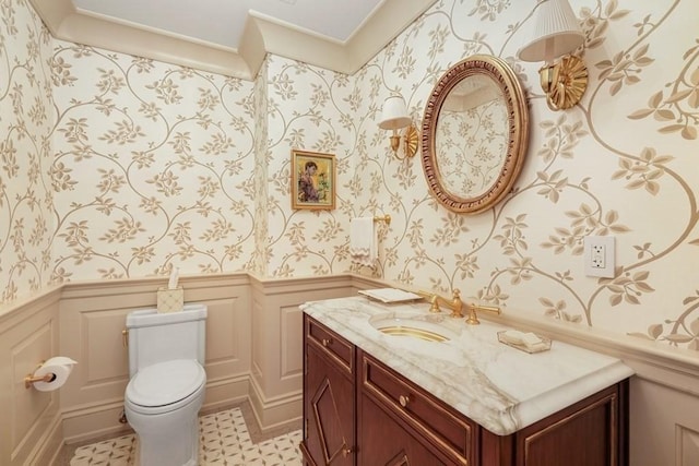 bathroom featuring a decorative wall, wainscoting, and wallpapered walls