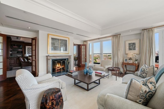 living room featuring a warm lit fireplace, baseboards, french doors, and ornamental molding