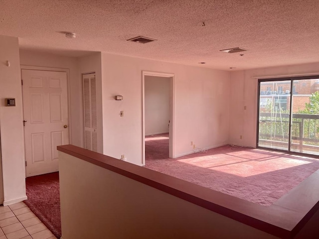 24 Corey St Unit 305, Everett, MA 02149 - empty room with light colored carpet, a textured ceiling, a smoke detector, and light tile patterned floors