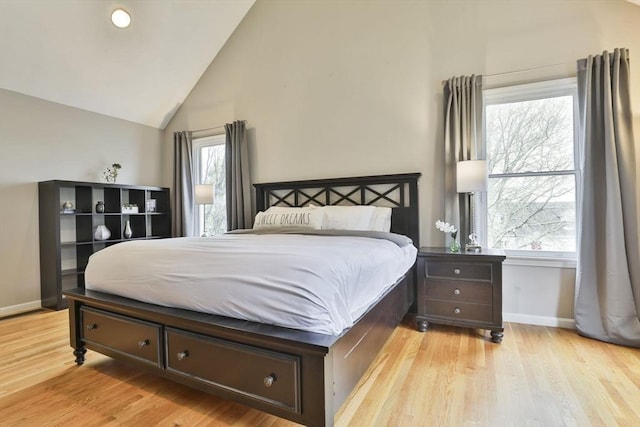 bedroom featuring baseboards, light wood-style floors, and high vaulted ceiling