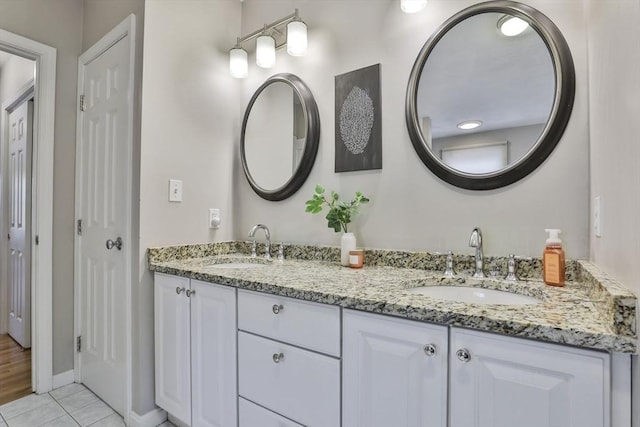 bathroom with a sink, baseboards, tile patterned flooring, and double vanity