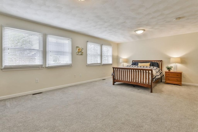 bedroom featuring baseboards, a textured ceiling, carpet floors, and visible vents