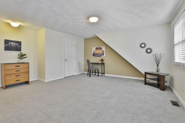 living area featuring baseboards, visible vents, and light carpet