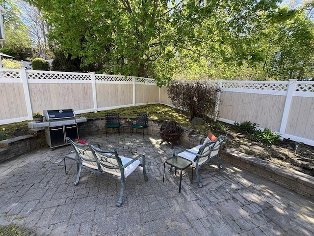 view of patio with area for grilling, a fire pit, and a fenced backyard