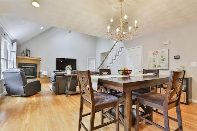 dining space with baseboards, stairway, a high end fireplace, a chandelier, and light wood-style flooring