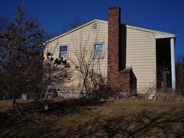 view of property exterior with a yard and a chimney